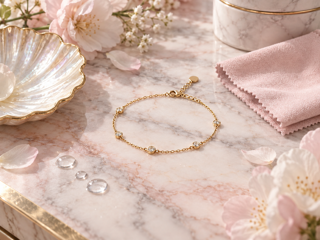 Bracelet doré NK Bijoux Paris sur marbre rose poudré avec fleurs et chiffon d’entretien